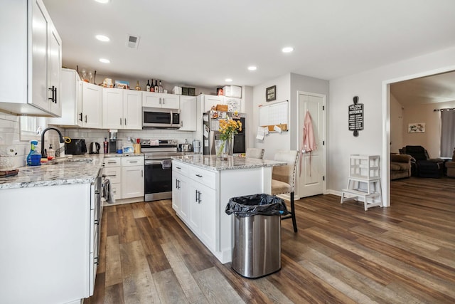 kitchen featuring white cabinets, sink, decorative backsplash, appliances with stainless steel finishes, and a kitchen island