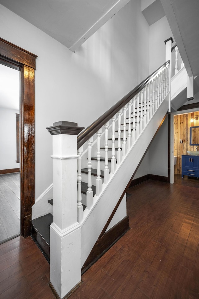 stairway with a towering ceiling, baseboards, and hardwood / wood-style flooring