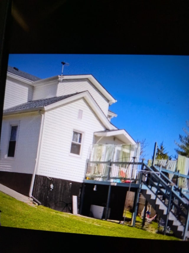 back of property with a lawn and stairway