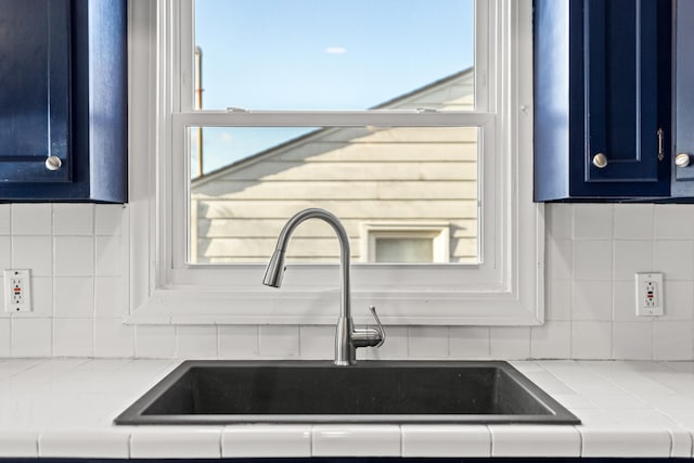 interior details featuring decorative backsplash, sink, and blue cabinets