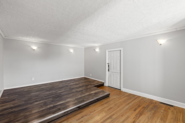 spare room with hardwood / wood-style floors, ornamental molding, and a textured ceiling