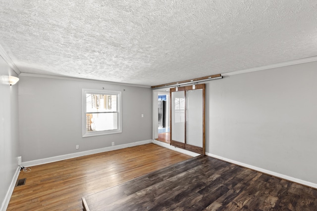 empty room featuring a textured ceiling, crown molding, and dark hardwood / wood-style floors