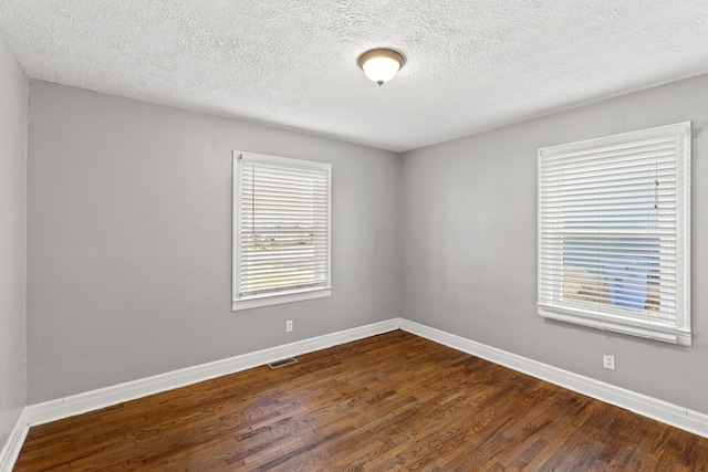 unfurnished room with a textured ceiling and dark wood-type flooring