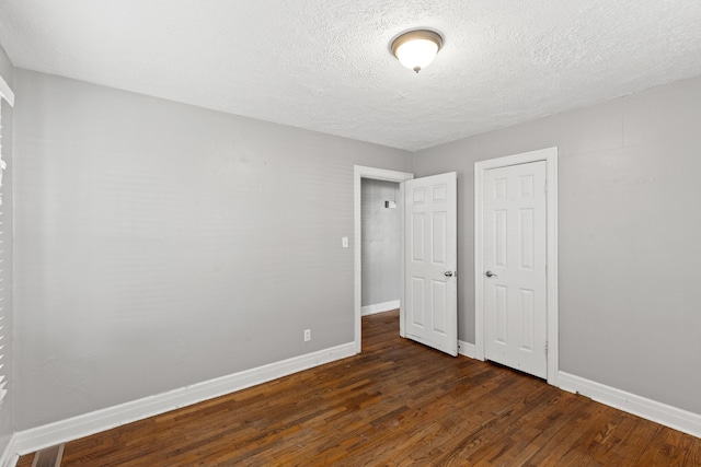 unfurnished bedroom featuring a textured ceiling, dark hardwood / wood-style flooring, and a closet