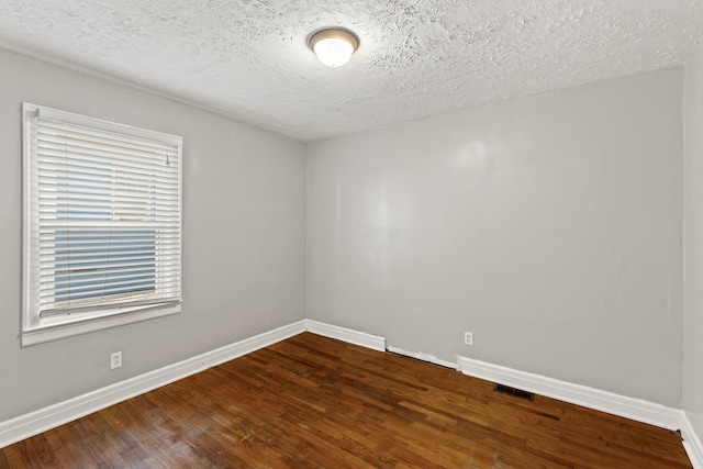 spare room featuring a textured ceiling and hardwood / wood-style flooring