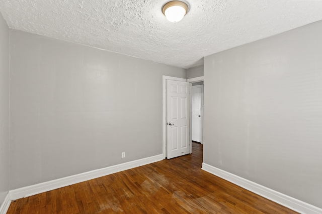 empty room featuring dark wood-type flooring and a textured ceiling