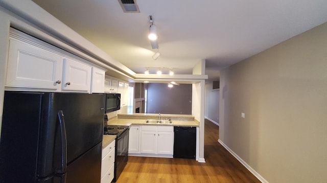 kitchen with black appliances, light countertops, light wood-style flooring, white cabinetry, and a sink