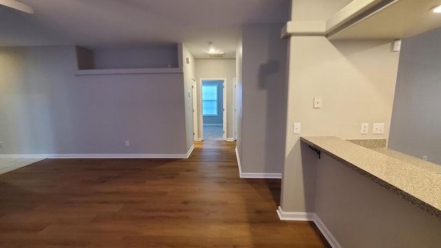 hall featuring visible vents, baseboards, and dark wood-style flooring