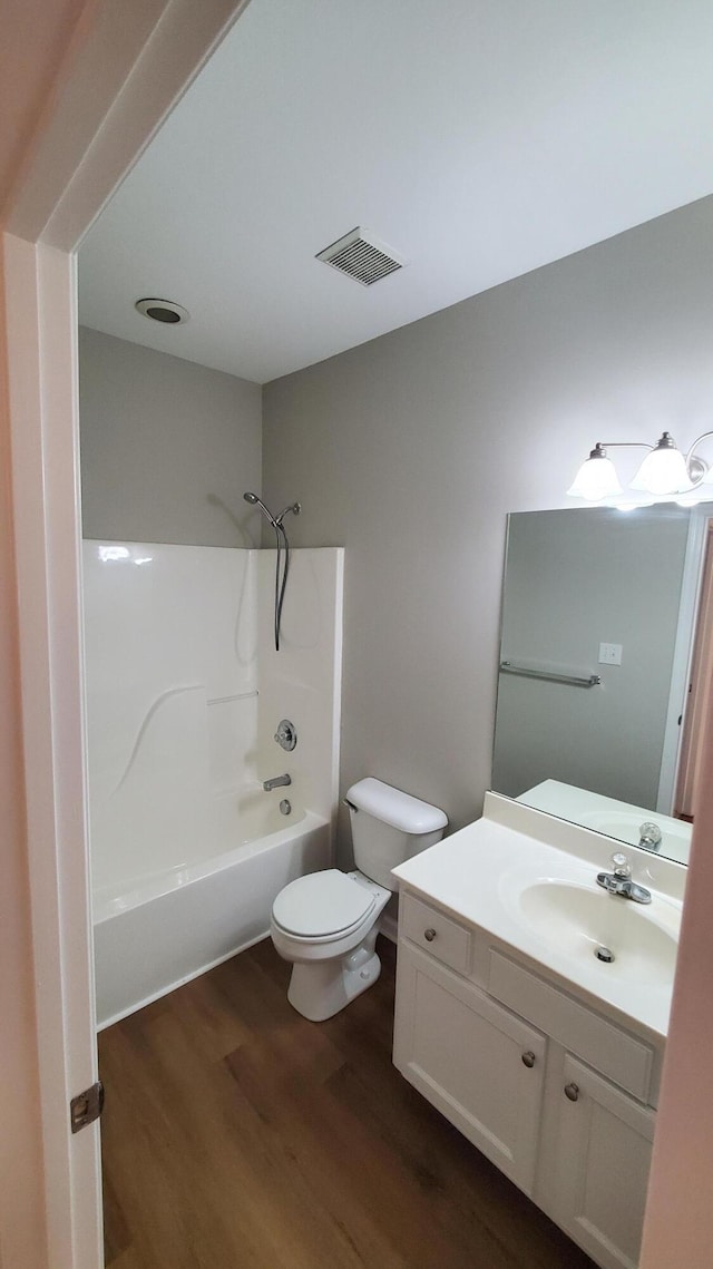 full bathroom with visible vents, toilet, wood finished floors, vanity, and shower / bathtub combination