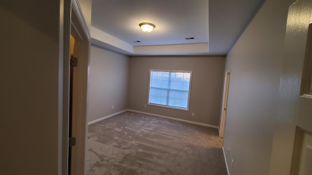 unfurnished room featuring baseboards, a raised ceiling, visible vents, and carpet flooring