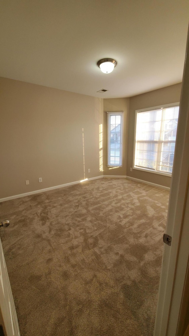 carpeted empty room featuring visible vents and baseboards