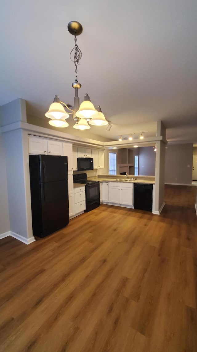 kitchen with black appliances, baseboards, decorative light fixtures, wood finished floors, and white cabinetry