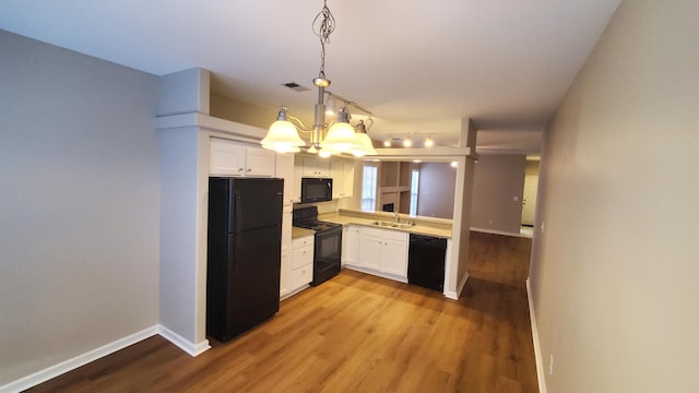 kitchen featuring white cabinets, black appliances, light countertops, and a sink