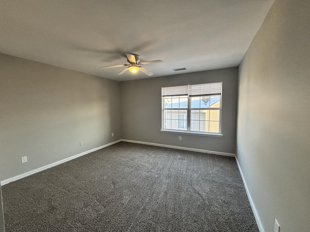 empty room with ceiling fan and dark colored carpet