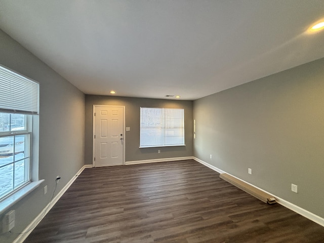 spare room with a wealth of natural light and dark hardwood / wood-style flooring