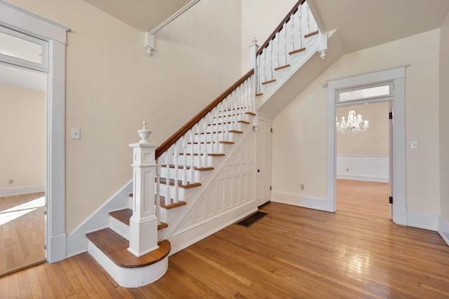 stairs with hardwood / wood-style flooring and a chandelier