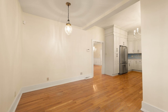 unfurnished living room featuring light wood-type flooring and an inviting chandelier