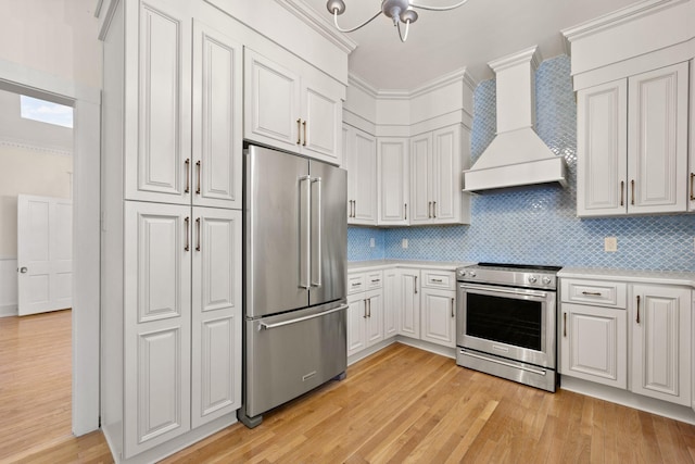 kitchen featuring light wood-type flooring, white cabinetry, premium range hood, and appliances with stainless steel finishes