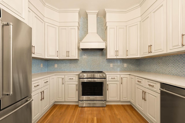 kitchen with backsplash, custom exhaust hood, light hardwood / wood-style floors, and stainless steel appliances