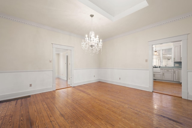 spare room with hardwood / wood-style floors and a notable chandelier