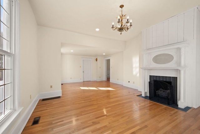 unfurnished living room with a fireplace, light hardwood / wood-style flooring, and a notable chandelier