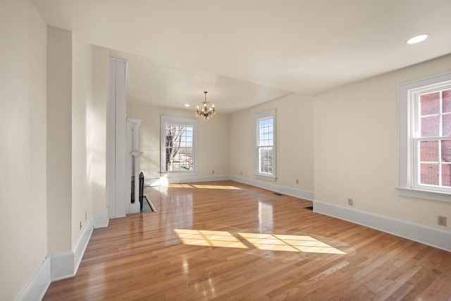 empty room with light hardwood / wood-style floors and an inviting chandelier