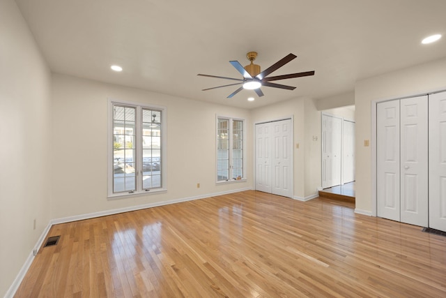 unfurnished bedroom with light hardwood / wood-style floors, ceiling fan, and multiple closets