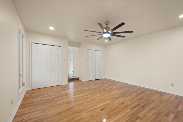 unfurnished bedroom featuring multiple closets, ceiling fan, and light hardwood / wood-style flooring