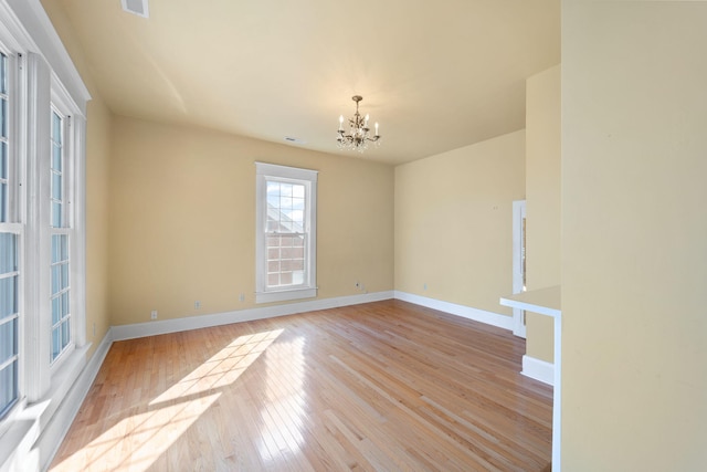 unfurnished room with a notable chandelier and light wood-type flooring