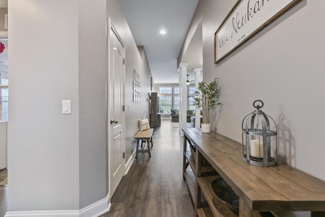 corridor featuring dark wood-type flooring, recessed lighting, baseboards, and decorative columns