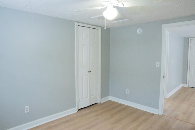 empty room with ceiling fan, light hardwood / wood-style floors, and a textured ceiling