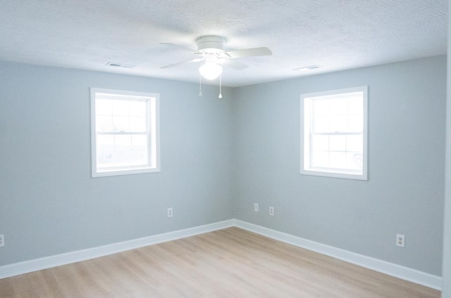 spare room featuring ceiling fan, a healthy amount of sunlight, a textured ceiling, and light hardwood / wood-style flooring