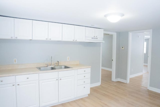 kitchen with sink, white cabinets, and light hardwood / wood-style flooring