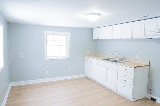 kitchen with exhaust hood, light wood-type flooring, white cabinetry, and sink