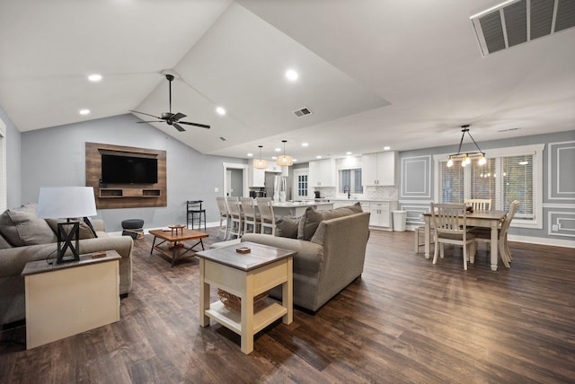 living room with vaulted ceiling, ceiling fan with notable chandelier, and dark hardwood / wood-style floors