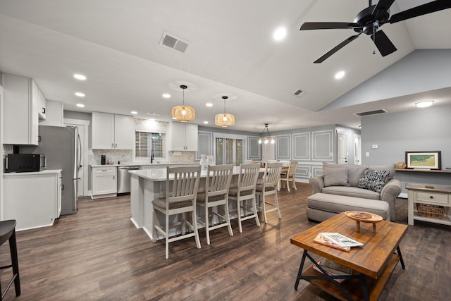 living room featuring ceiling fan, high vaulted ceiling, and dark wood-type flooring