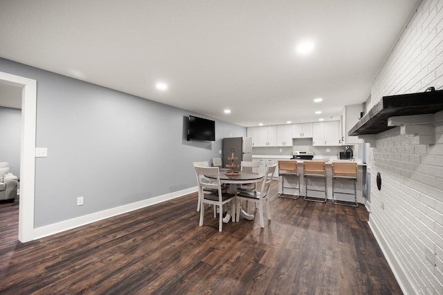 dining space featuring dark wood-type flooring and brick wall