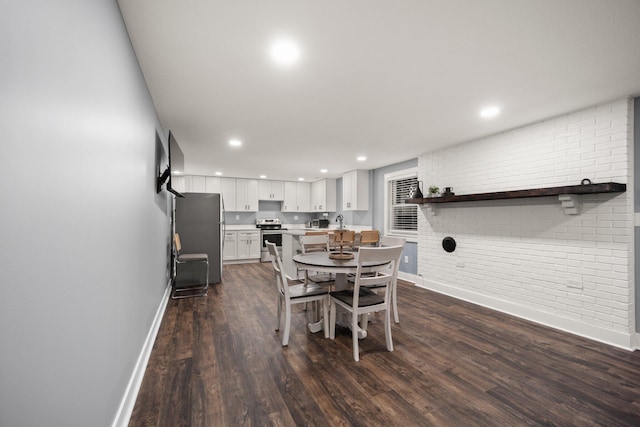 dining area with dark hardwood / wood-style flooring and brick wall