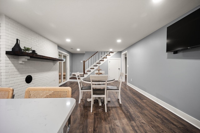 dining room with dark wood-type flooring and brick wall