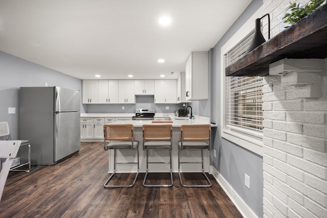 kitchen featuring sink, stainless steel appliances, kitchen peninsula, a kitchen bar, and white cabinets