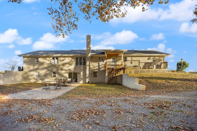 rear view of house with a wooden deck and a patio