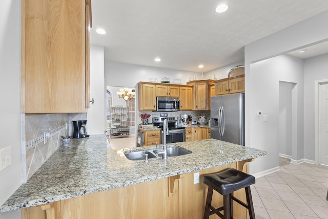 kitchen featuring light stone counters, kitchen peninsula, appliances with stainless steel finishes, and tasteful backsplash