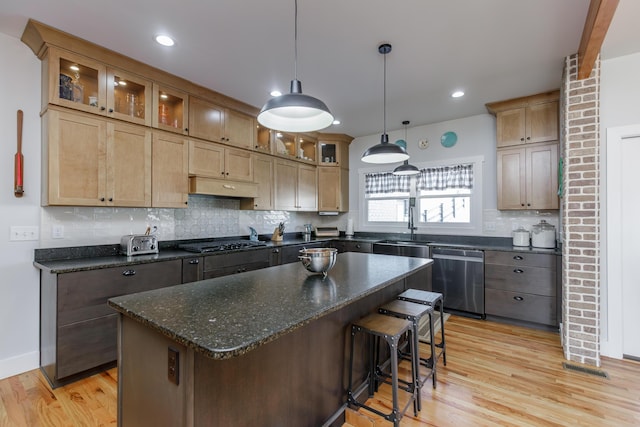 kitchen featuring a center island, hanging light fixtures, stainless steel appliances, light hardwood / wood-style floors, and a breakfast bar