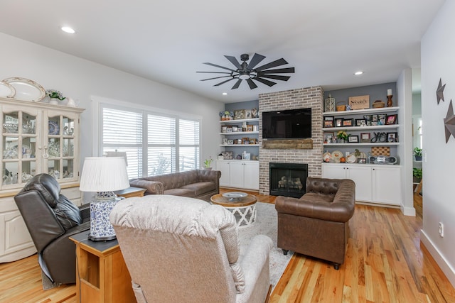 living room with ceiling fan, a fireplace, and light hardwood / wood-style floors