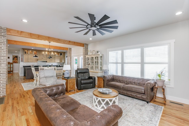 living room with ceiling fan with notable chandelier and light hardwood / wood-style floors