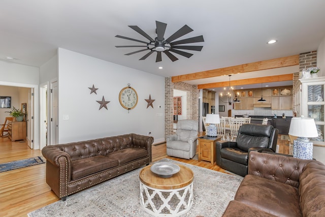 living room with ceiling fan with notable chandelier, light wood-type flooring, and brick wall