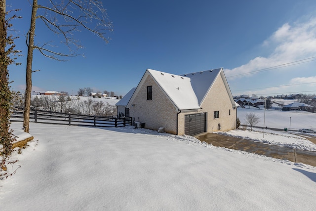 snow covered back of property featuring a garage