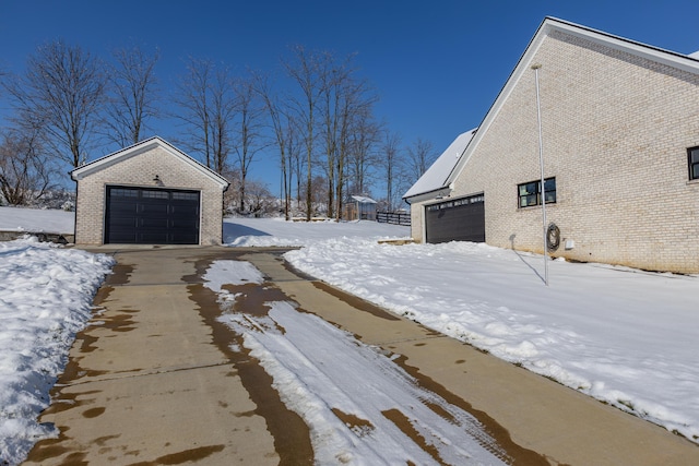 yard covered in snow featuring a garage and an outbuilding