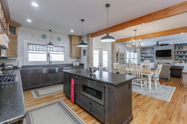 kitchen featuring beam ceiling, backsplash, sink, and a kitchen island