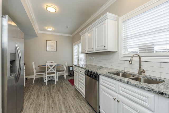 kitchen featuring sink, white cabinetry, light stone counters, ornamental molding, and stainless steel appliances